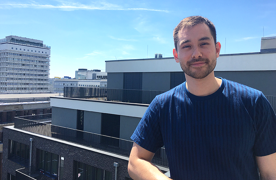 Man leaning on railing, on balcony in Berlin, smiling at camera